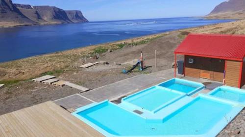 TalknafjordurGuesthouse Tálknafjörður的站在一座带两个游泳池的建筑旁边的男人