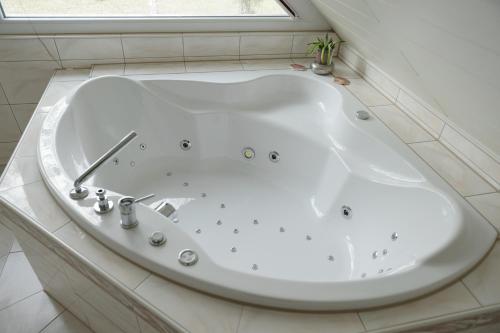 柏林Ferienhaus direkt an der Spree mit Whirlpool und Sauna的带窗户的浴室内的白色浴缸
