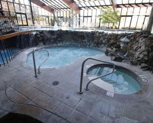 Vernon Township10 guest Ski Chalet Pools Golf Ski Hike的一座石头墙建筑中的热水浴缸