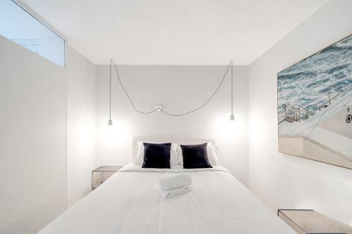 悉尼Stylish 1BR Haven in Bondi Junction的卧室配有一张白色床,墙上挂有绘画作品