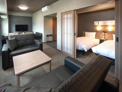 沼田Hotel Route Inn Numata的酒店客房,设有两张床和一张沙发