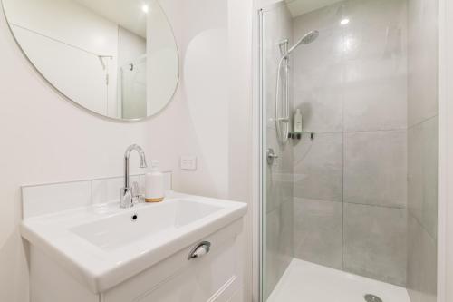 基督城Retro Retreat in Christchurch的白色的浴室设有水槽和淋浴。