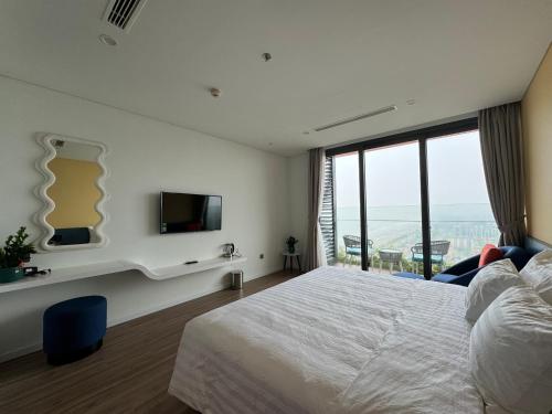 Nam KhêFlamingo Ibiza Hải Tiến的一间卧室设有一张床、一台电视和一个窗口。