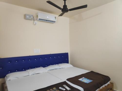 GokarnRedkar Rooms Gokarna Beach front AC And Non AC Rooms的一间卧室配有一张带蓝色床头板的床和风扇。