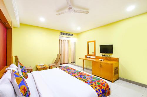 钦奈FabHotel Prime Mahalaya Residency的一间卧室配有一张床、一张书桌和一台电视