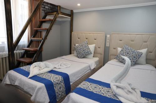 SeyhanThe Time Hotel Adana的客房设有两张床和一个带天鹅毛巾的楼梯。