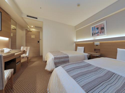东京Keio Presso Inn Otemachi的酒店客房配有两张床和一张书桌