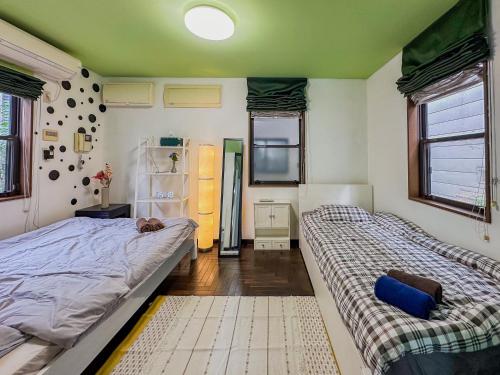 东京Tranquil Tokyo Retreat #Spacious 3BR House in Hiroo的一间卧室配有两张床和一台冰箱