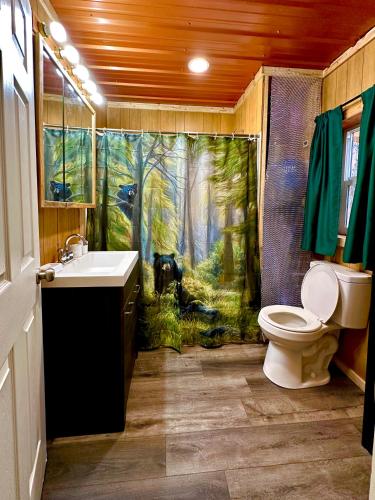 托克Roberts Lodge的浴室设有淋浴帘,森林里饲养着一只狗
