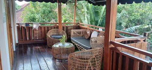 马塔兰Dewi Sri Guesthouse的门廊配有藤椅、桌子和雨伞