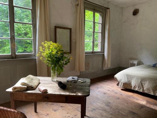 Soultzbach-les-BainsLes anciens thermes的卧室配有一张桌子,上面有花瓶