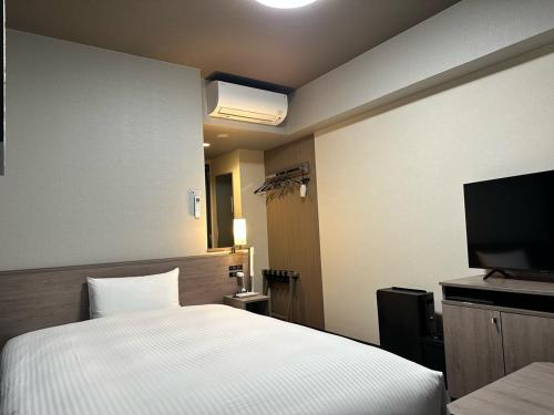 福岛Hotel Route Inn Fukushima Nishi Inter的一间卧室配有一张床和一台平面电视