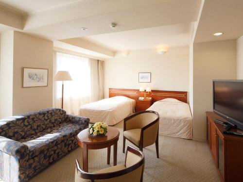 北九州小仓皇冠饭店的一间配备有沙发及电视的酒店客房