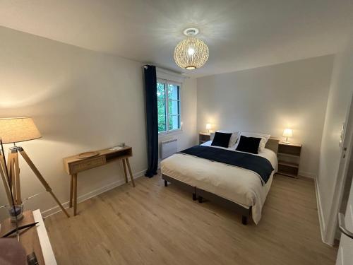 GravesLe Clos des Lilas的一间卧室配有一张床、一张桌子和一盏灯