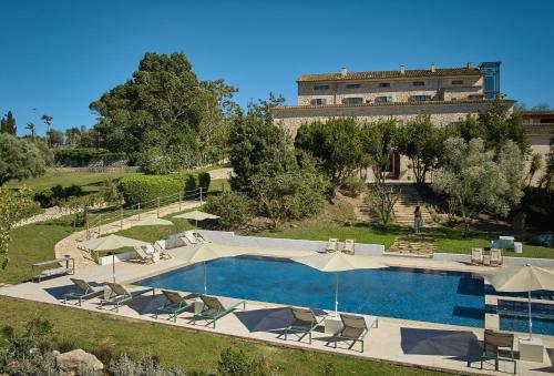 蒙图伊里Es Figueral Nou Hotel Rural & Spa - Adults Only - Over 12的一个带椅子的游泳池和一个背景建筑