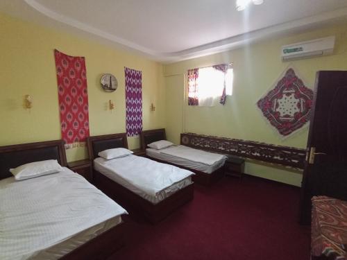 希瓦Khiva Saodat Guest House的客房设有两张床、一个窗户和两个窗户。