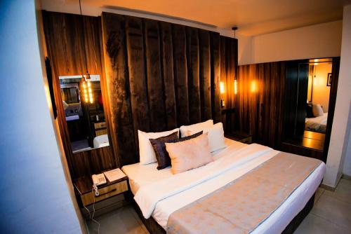 阿沙巴Vic & J Lounge and Hotel Asaba的一间卧室设有一张带木墙的大床