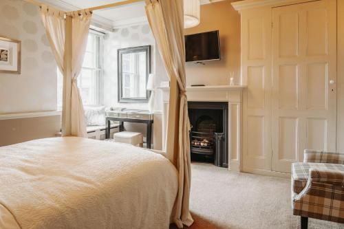 惠灵顿Old Orleton Inn的一间卧室设有一张天蓬床和一个壁炉