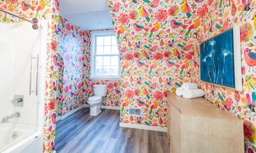 麦基诺岛The Inn at Stonecliffe的浴室拥有色彩缤纷的墙纸、卫生间和浴缸。