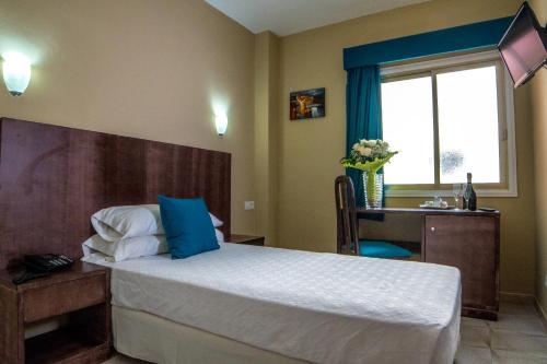 圣伊西德罗Hotel Aeropuerto Sur的一间卧室配有一张床、一张书桌和一个窗户。