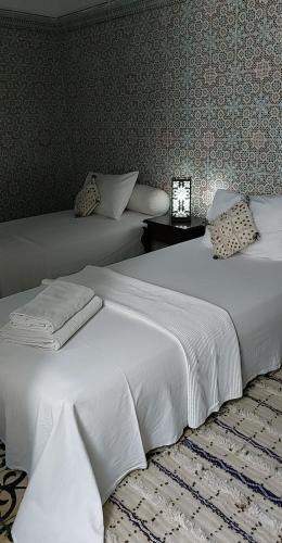 拉巴特Riad Diafa的卧室设有两张白色的床和墙壁