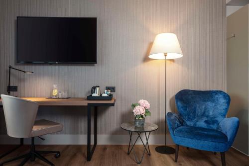 柏林NH酒店柏灵选帝侯大街店的客房配有书桌、蓝椅和灯具