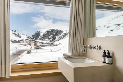 祖尔斯A-ROSA Collection Hotel Thurnher's Alpenhof的浴室享有白雪 ⁇ 的山景