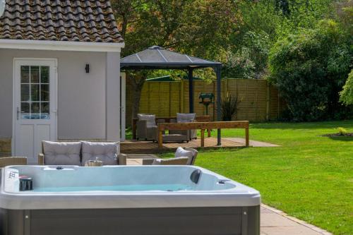 伯利Oak Lodge的庭院内的热水浴池,配有桌子和长凳