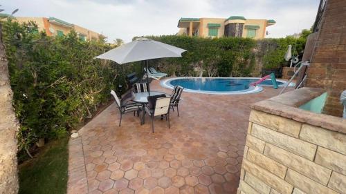 阿莱曼Villa123的游泳池旁配有遮阳伞的桌椅