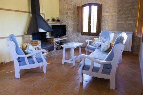 瓦德诺比斯Masia Villa Pilar Valderrobres的客厅配有三把椅子和壁炉