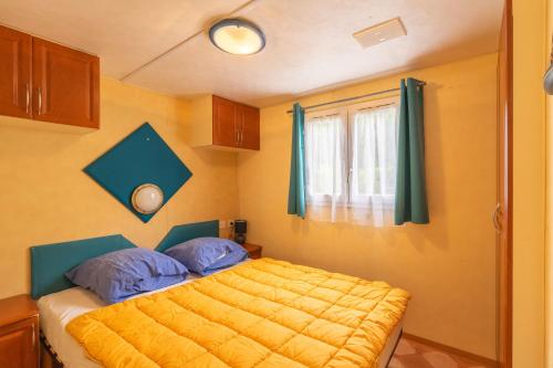 拉特里姆莱德Mobilhome Mh 212的一间卧室配有一张带黄色床单的床和一扇窗户。