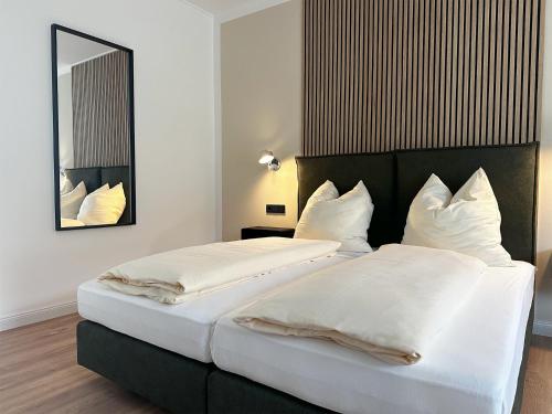 巴特洪内夫Weingut Pieper - Vinothek & Hotel am Drachenfels的配有镜子的酒店客房内的两张床