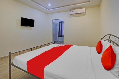 瓦朗加尔OYO Flagship Hotel Vathsalya的一间卧室配有一张带红色枕头的床和一台电视。