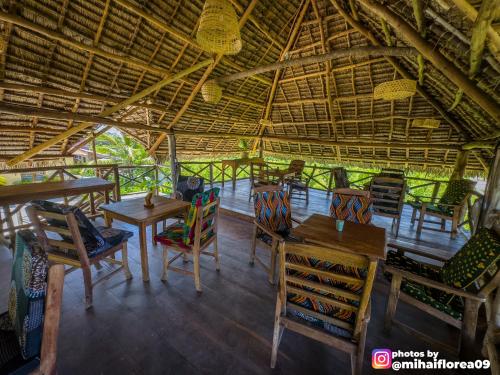 MakunduchiTofauti Inn的一间稻草屋顶餐厅,配有桌椅