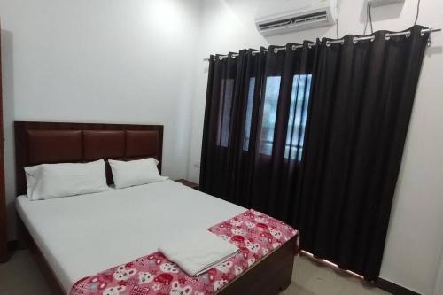 瓦拉纳西Champaran Home Deluxe的一间卧室配有床和黑色窗帘