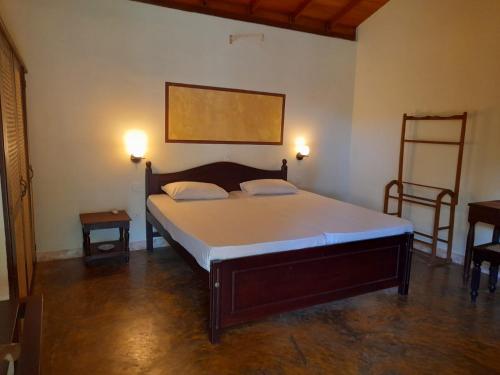 贝鲁沃勒Seetharama Garden of Life的一间卧室配有一张带两盏灯和两张桌子的床。