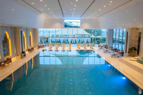 巴格达Babylon Rotana Hotel的大楼内带桌椅的大型游泳池