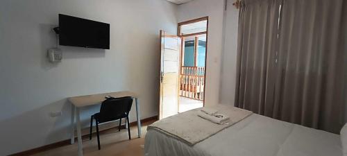 卡哈马卡Hotel Aural的一间卧室配有一张床、一张书桌和一台电视