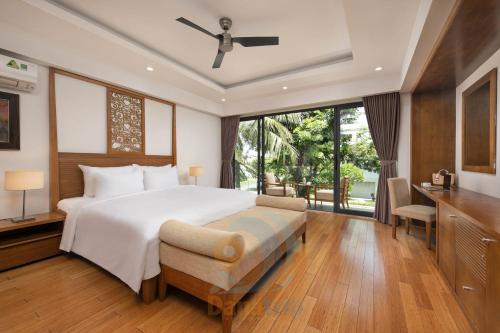 岘港Ocean Beach Resort Da Nang的卧室配有一张白色大床和一张书桌