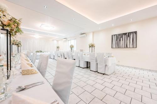 科希策Hotel Zlaté Košice的宴会厅配有白色的桌子和白色的椅子