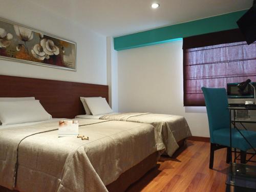 利马Hotel Vila Santa的一间卧室配有两张床、一张桌子和一把椅子