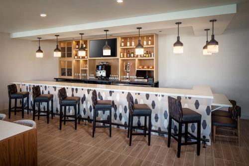 斯科茨Hyatt Place Scottsdale North的餐厅里的酒吧,周围摆放着椅子