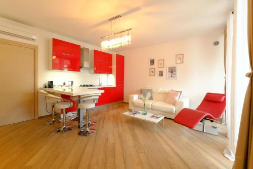 米兰马瑞提那MIMA61 - Appartamento con giardino e posti auto a 50mt dal centro的厨房以及带红色橱柜和沙发的客厅。