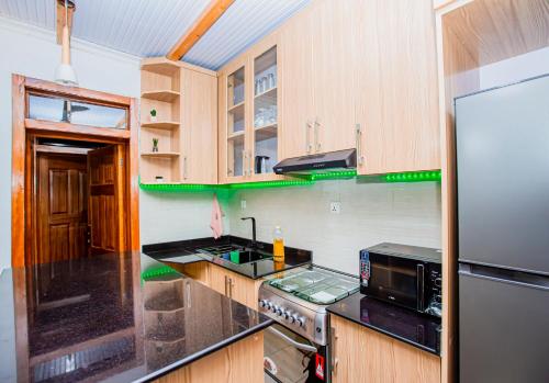 基加利Guest Suite in Kigali的厨房配有木制橱柜和不锈钢冰箱。