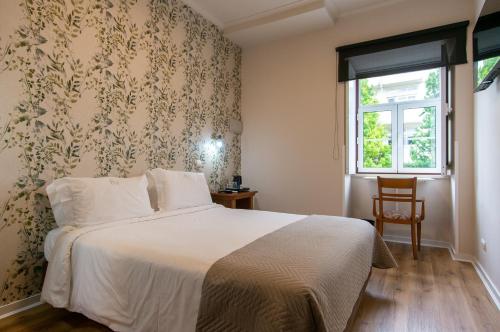 科英布拉维多利亚酒店 的一间卧室设有一张床和一个窗口