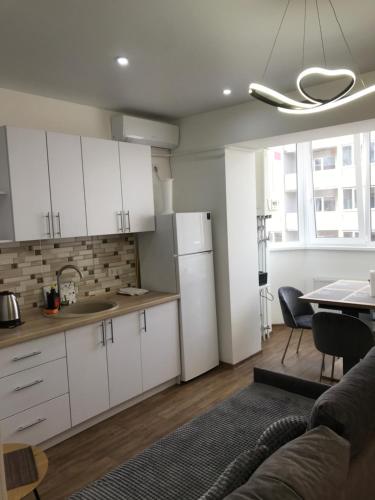 切尔尼戈夫Light Apartments的厨房以及带白色橱柜和桌子的客厅。