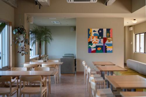 真鹤町HOTEL FARO manazuru - Vacation STAY 56476v的餐厅设有桌椅,墙上挂有绘画作品