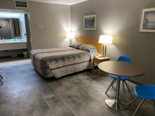 大草原城Stanford Inn & Suites的酒店客房带一张床、一张桌子和椅子