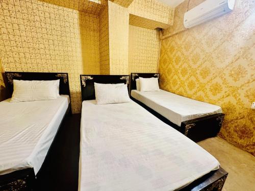 JhelumJhelum Khan Hotel的黄色墙壁客房中的两张单人床