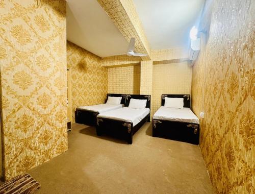 JhelumJhelum Khan Hotel的配有两张床铺的黄色墙壁客房